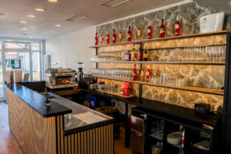 Elegante Bar von DIVINO in Hallbergmoos mit Espressomaschine, Weinflaschen, Gläserregalen und langer Theke