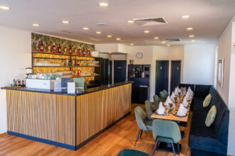 Im Innenraum des DIVINO in Hallbergmoos stehen eine stilvolle Bar und gedeckte Tische im Restaurantbereich.