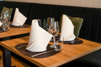 Gedeckter Holztisch im DIVINO Hallbergmoos mit gefalteten Servietten, Weingläsern und stilvoller Bistro-Tischdekoration